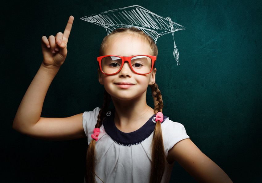 Genius girl in red glasses near blackboard in master hat